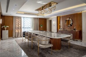 A modern dining area with a long table, multiple chairs, and a decorative ceiling light fixture. - Triumph Luxury Hotel (CAIRO)