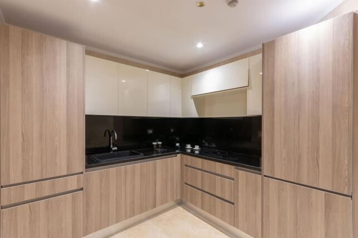 A modern kitchen with wooden cabinets, a black countertop, and a stainless steel sink.