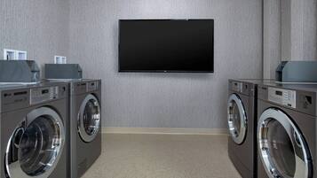 Un lavadero con dos lavadoras LG de carga frontal y un televisor de pantalla plana montado en la pared.