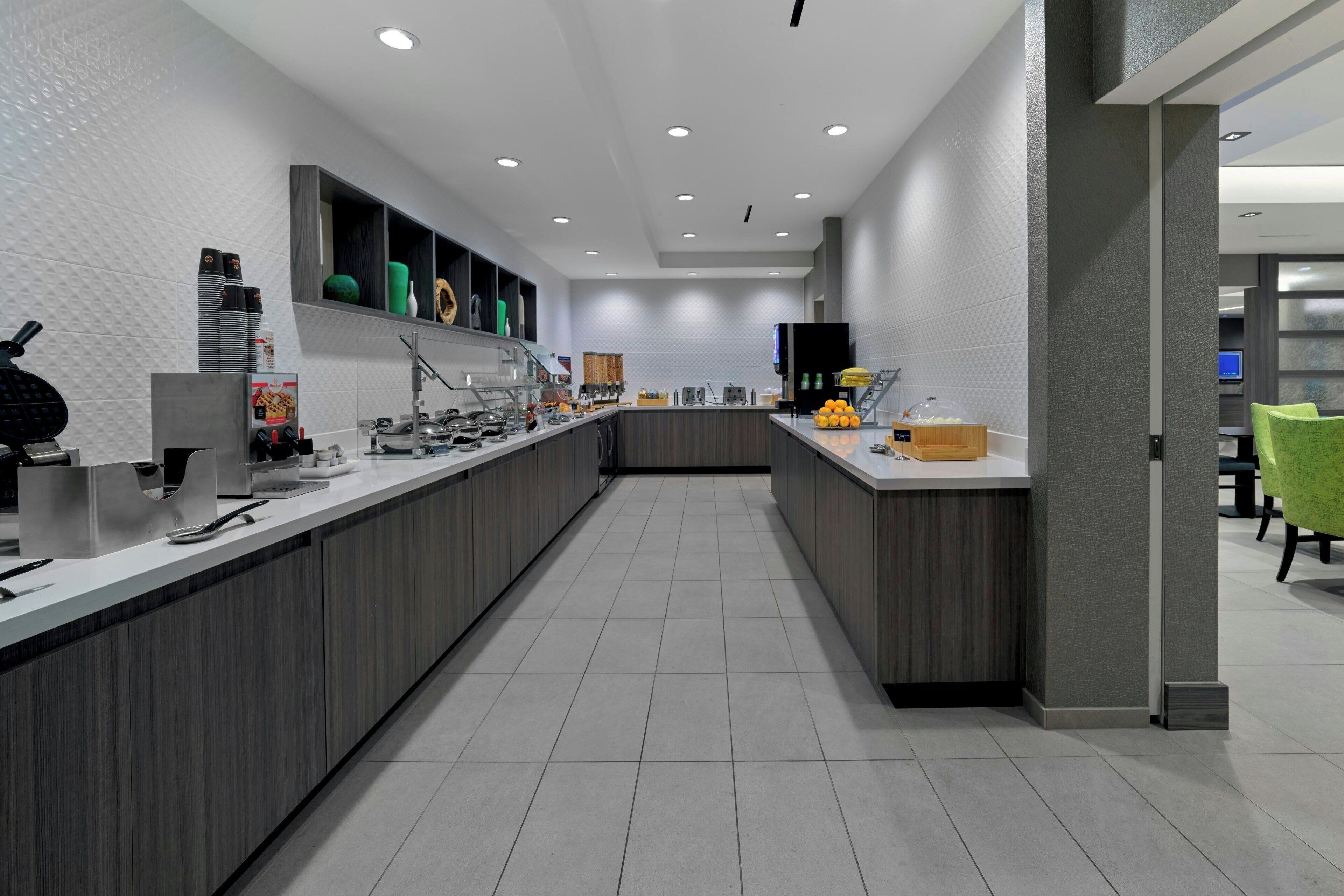 A modern kitchen with a long counter, built-in appliances, and a tiled backsplash.