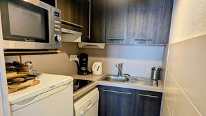 A compact kitchen with a microwave, coffee maker, sink, and dishwasher.