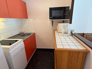 A compact kitchen with a dishwasher, a microwave, and a coffee maker on the countertop.