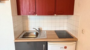 A compact kitchenette with a sink, a small refrigerator, and a countertop.
