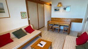 A room with a sofa, a wooden table, a bench, and a dining table with chairs.