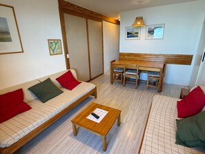 Ein Zimmer mit einer Couch, einem Holztisch, einer Bank und einem Esstisch mit Stühlen.