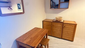A wooden dining table with benches, a wooden cabinet with drawers, a hanging light fixture, and a framed picture on the wall.