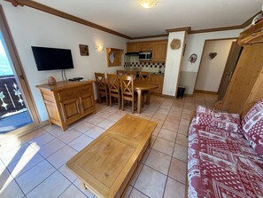 A compact living space with a dining area, kitchenette, and a sofa. - 3-room luxury apartment at the foot of the slopes with private parking (Les Adrets-Prapoutel)