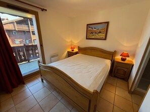 Ein Schlafzimmer mit einem hölzernen Bett, zwei Nachttischlampen, einem Fenster mit Blick auf Gebäude und einem Bild an der Wand.