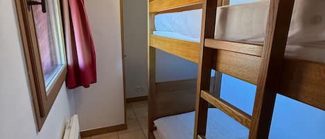 A bunk bed room with a window, a radiator, and a door.
