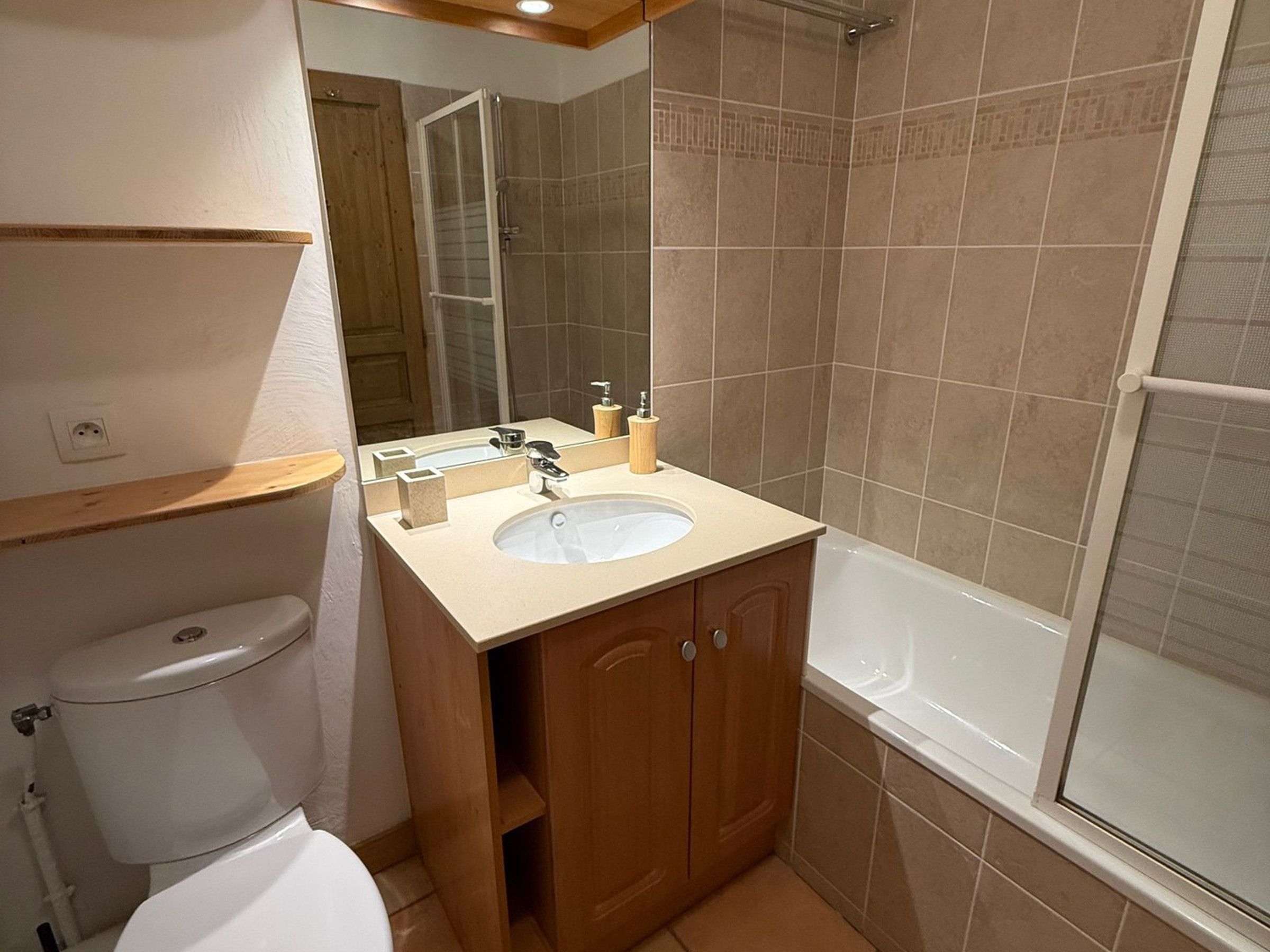 A bathroom with a toilet, sink, mirror, and bathtub.