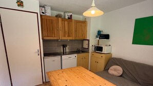 A compact kitchen with wooden cabinets, a microwave, and a dining table.