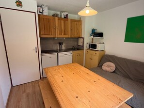 A compact kitchen with wooden cabinets, a microwave, and a dining table.