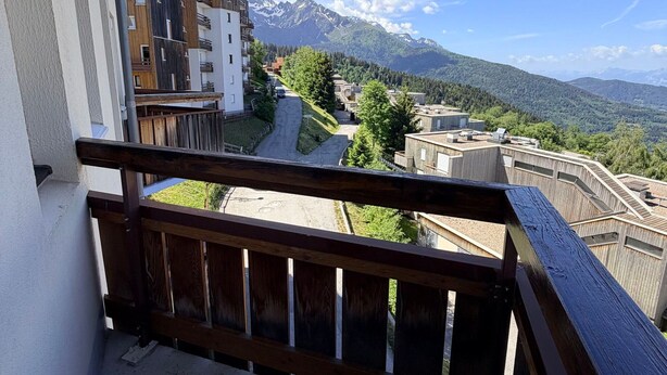 A residential area with modern buildings, a wooden balcony, and a mountain view.