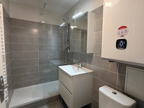 Um banheiro moderno com chuveiro, pia e vaso sanitário.