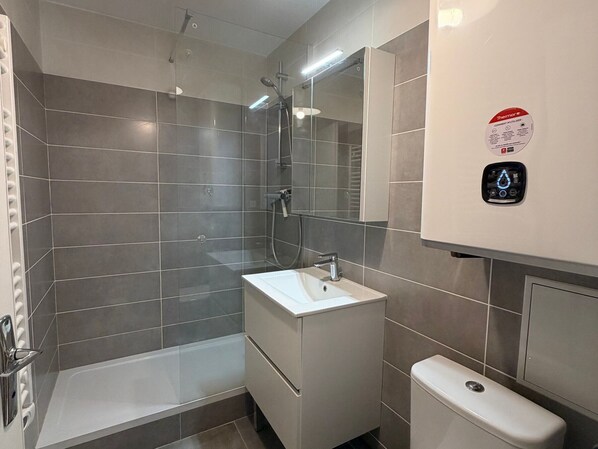 A modern bathroom with a shower, sink, and toilet.