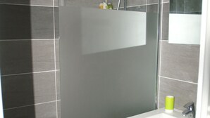 Een badkamer met een witte wastafel, een spiegel en een douchehoek.