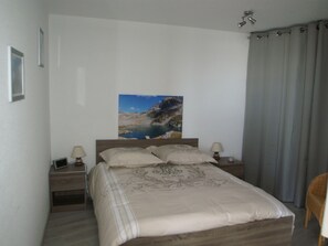 A bedroom with a bed, two bedside tables, a night lamp, a picture on the wall, and a window with curtains. - Charming 3-room apartment with balcony (Les Adrets-Prapoutel)