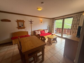 A cozy room with a wooden table, a sofa, and a large window with a view of a garden.
