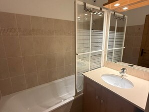 Un bagno con vasca, lavandino e cabina doccia in vetro.