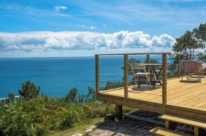 A wooden deck with outdoor seating overlooking a coastal view. - House with sea view under the Morgat lighthouse (Crozon)