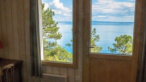 Une chambre avec un lit, une fenêtre donnant sur la mer et une porte.