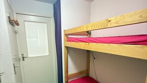A room with a bunk bed, a door, and a curtain.