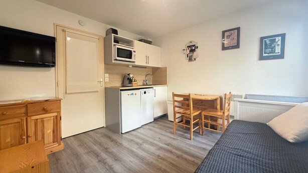 A compact room with a kitchenette, a bed, a TV, and a dining area.
