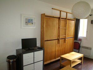 A room with a wooden wardrobe, a desk, a chair, and a television. - Cozy studio in station center, slopes view (Les Adrets-Prapoutel)