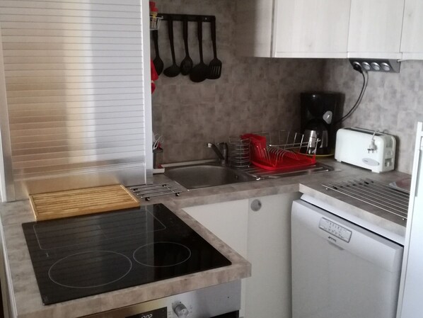 A compact kitchen with a built-in stove, a small refrigerator, and a toaster.