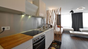 A modern kitchen with a central island, built-in oven, and a dining area with a sofa and a coffee table. - 3 Bathroom - Rhapsody In Roof - Penthouse (München)
