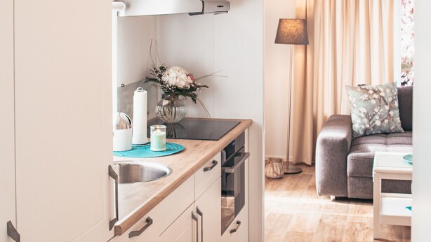 A modern kitchen with white cabinets, a built-in oven, and a countertop with a sink.
