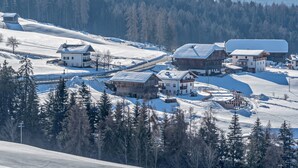 Un pueblo cubierto de nieve con casas de madera tradicionales, un telesilla y una montaña boscosa al fondo.
