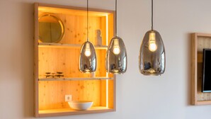 Une étagère en bois avec un miroir, un bol et une petite plante.