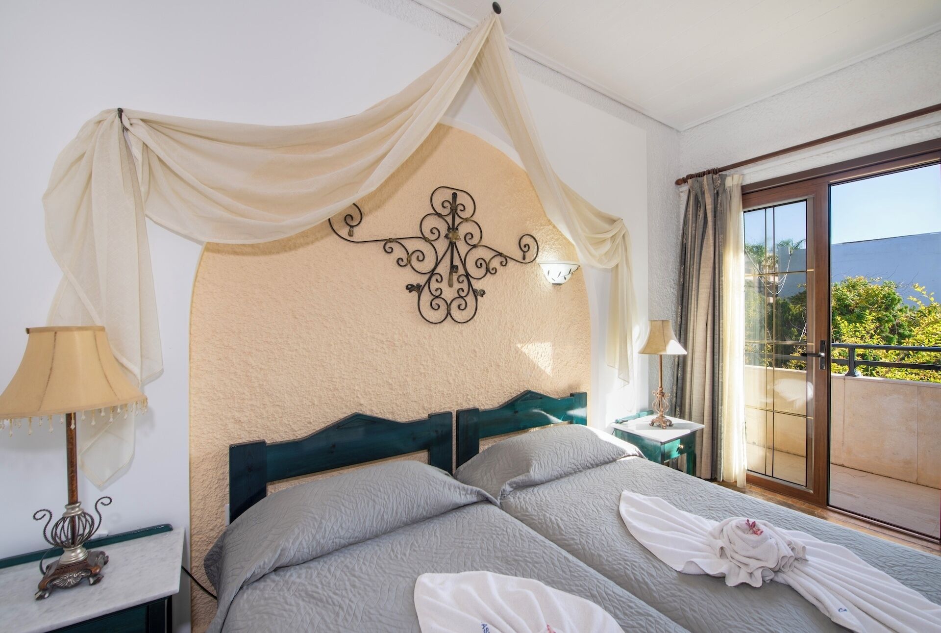 Habitación de hotel con cama, dos lámparas de noche, un adorno en la pared, una mesita de noche y vistas a zonas verdes.