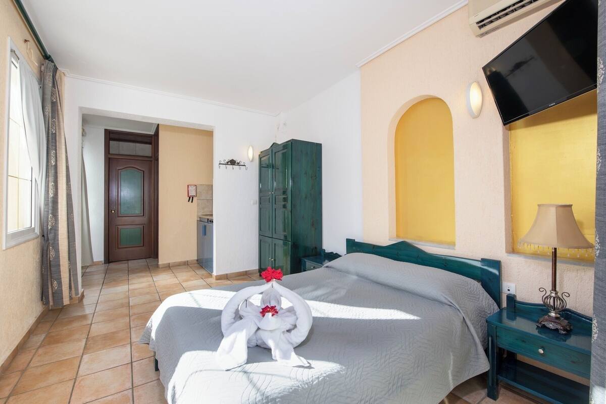 A hotel room with a bed, a desk, a wardrobe, and a TV.