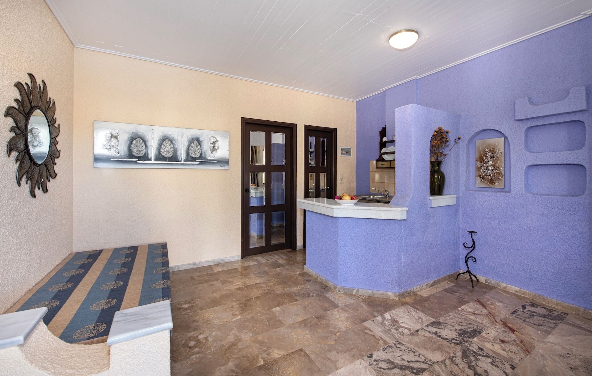 Um corredor com piso de mármore, um banco, uma porta e uma parede com detalhes decorativos.