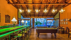 A billiards room with a pool table, multiple chairs, and hanging chandeliers. - Hotel Castle Suites (Platanias)