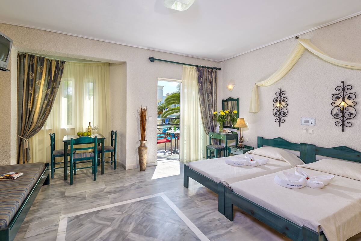 A hotel room with a bed, a desk with a chair, a TV, and a view of the pool area.