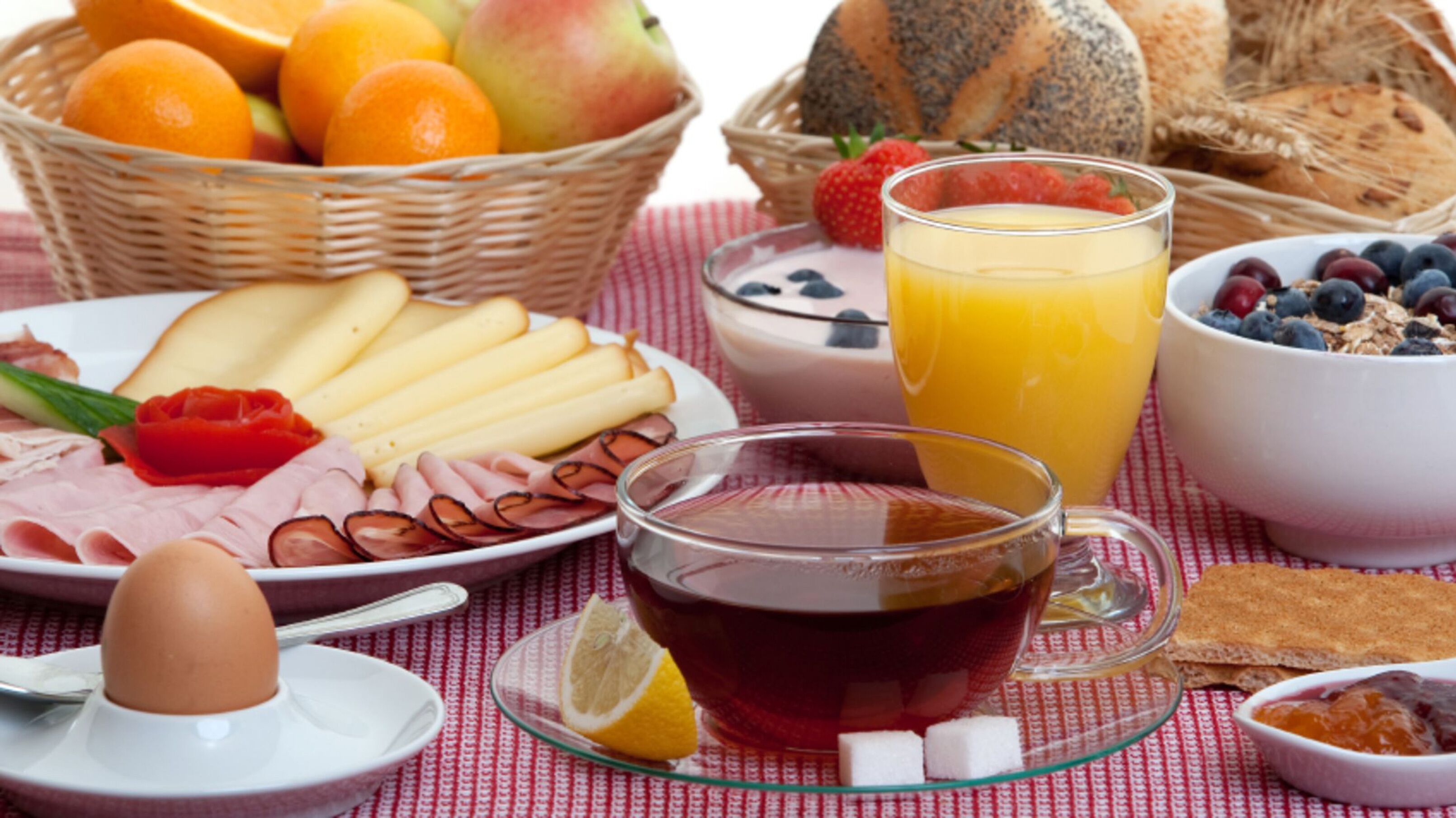 Un desayuno con una variedad de alimentos, incluyendo frutas, pan y una taza de té.