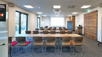 A conference room with a large table, multiple chairs, a projector screen, and a whiteboard.