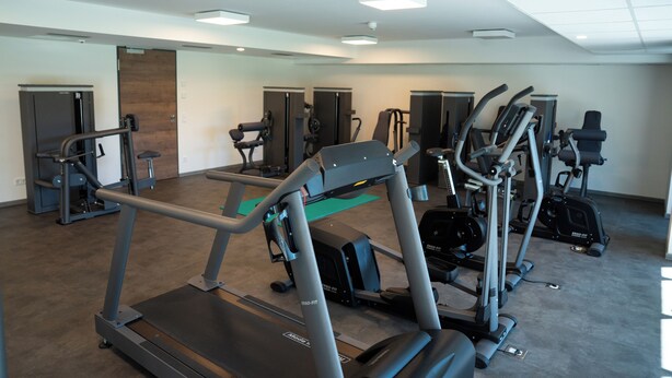 Un gimnasio con cintas de correr, elípticas y equipo de pesas.