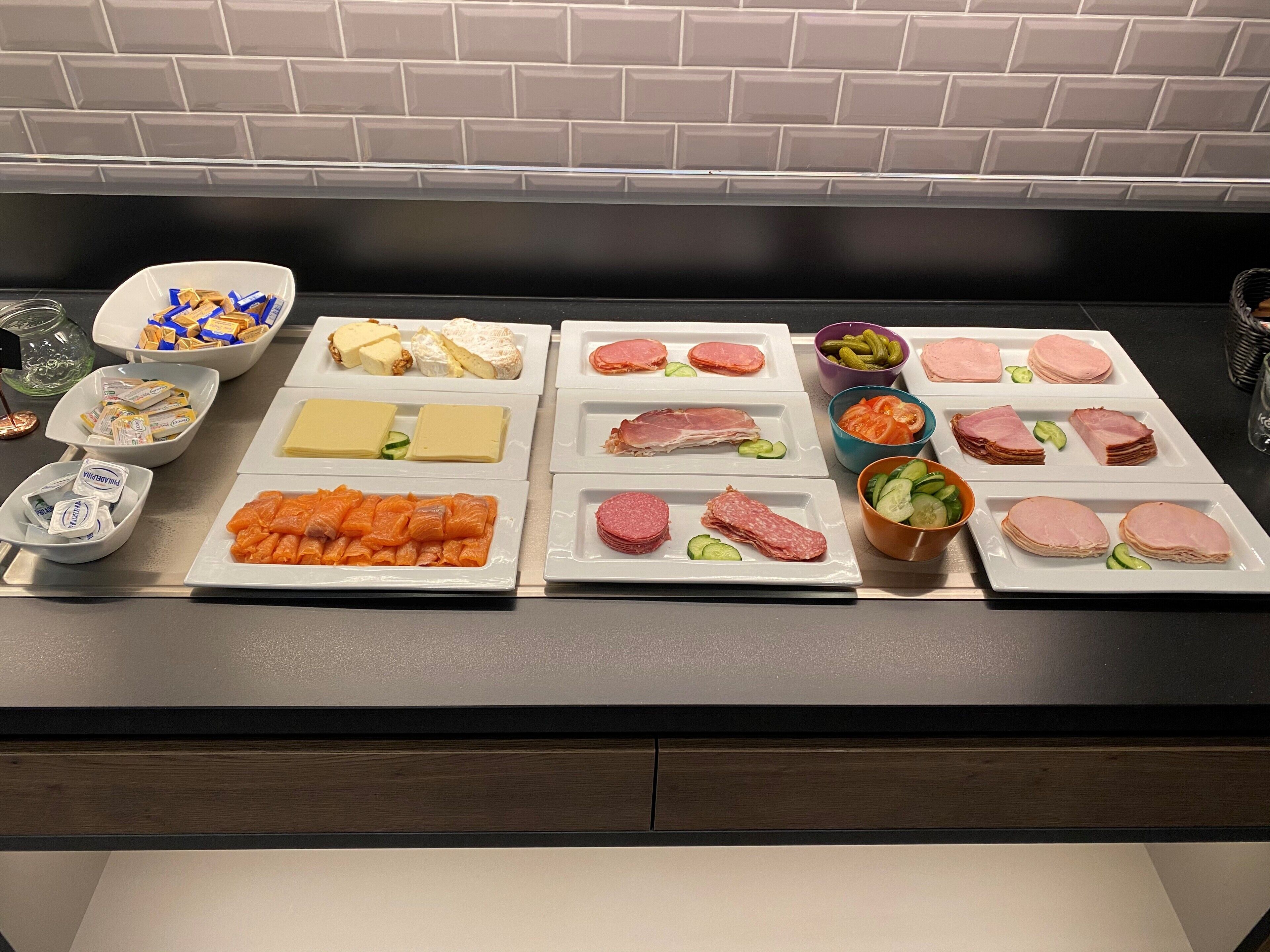 A buffet table with various food items including cheeses, meats, and vegetables.