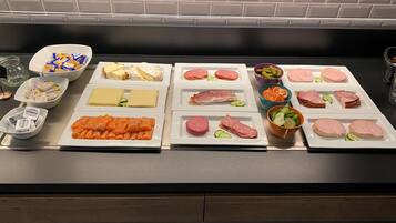 A buffet table with various food items including cheeses, meats, and vegetables.