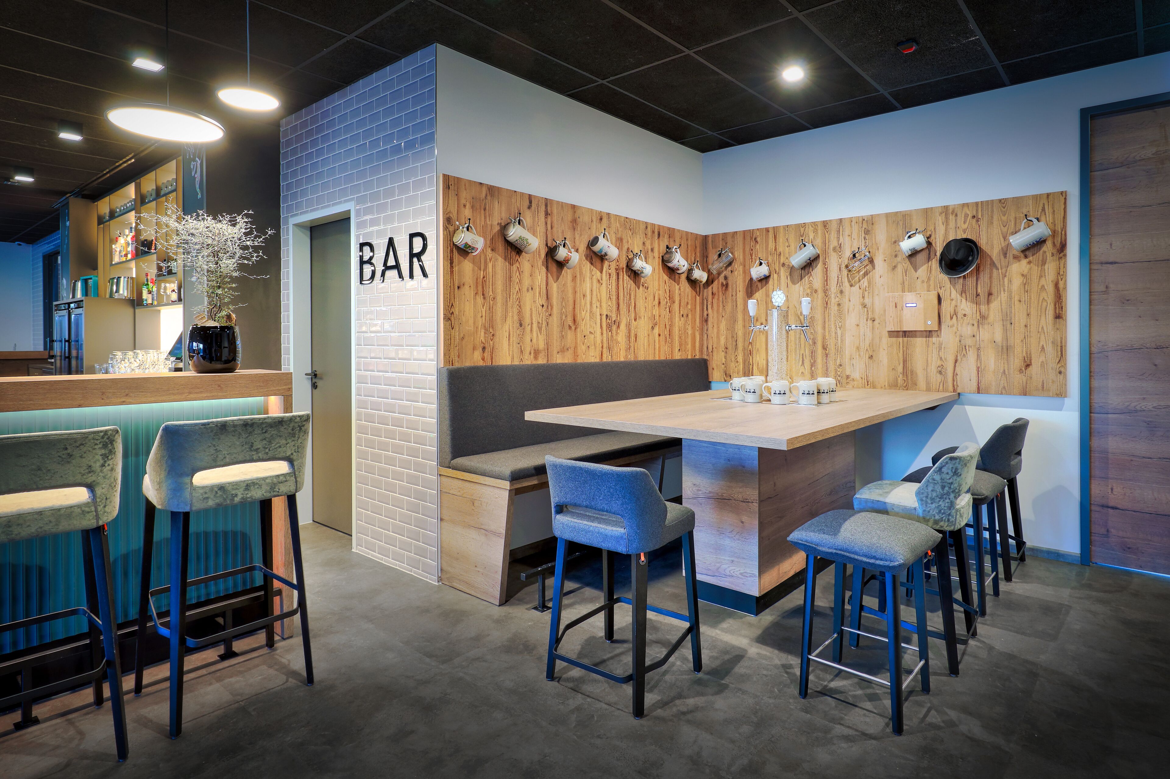 A bar area with a wooden accent wall, bar stools, and a counter.