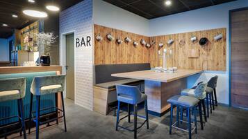 A bar area with a wooden accent wall, bar stools, and a counter.