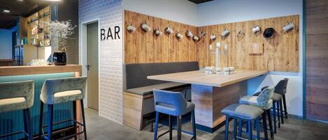 Una zona de bar con una pared de acento de madera, taburetes y una barra.