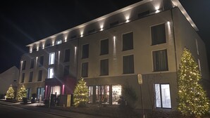 Un hotel moderno con varios pisos, amplias ventanas y una fachada bien iluminada.