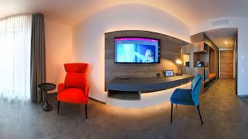 Una habitación de hotel moderna con cama, escritorio, televisión y zona de estar.