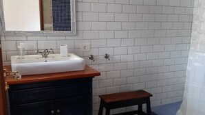 A bathroom with a white sink, mirror, and tiled walls. - Charming Refurbished 18th Century Cottages in Arico Nuevo (Arico)