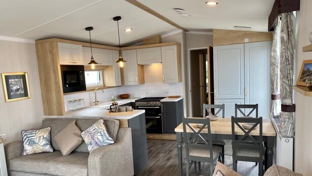 A compact living space with a kitchenette, a dining area, and a sofa set. - The Lizard Bluewater (Helston)